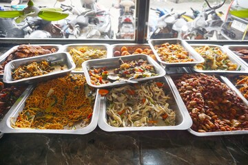 Various cooked Indonesian dishes displayed in a restaurant, showcasing a variety of local flavors with an appetizing presentation.