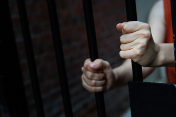 Women's hands holding prison railings