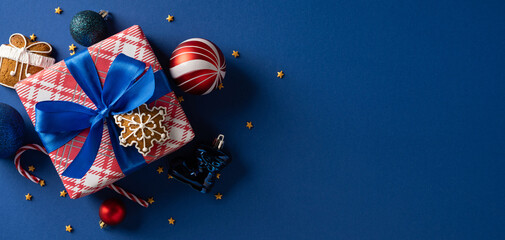 A red plaid gift box tied with a vivid blue ribbon sits on a dark blue background, surrounded by...