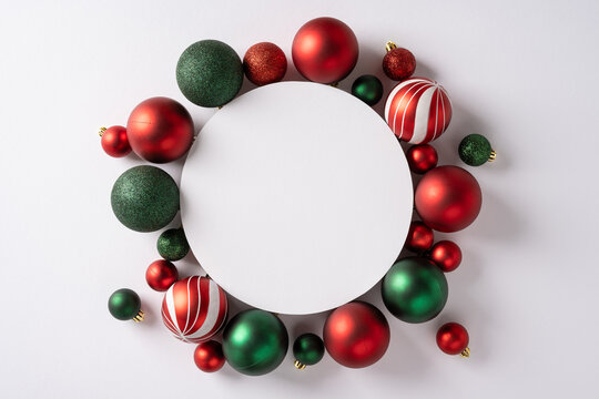 A festive circle of red and green Christmas ornaments frames a clean white center, conveying holiday celebration, seasonal warmth, and cheerful greeting for the New Year - Powered by Adobe