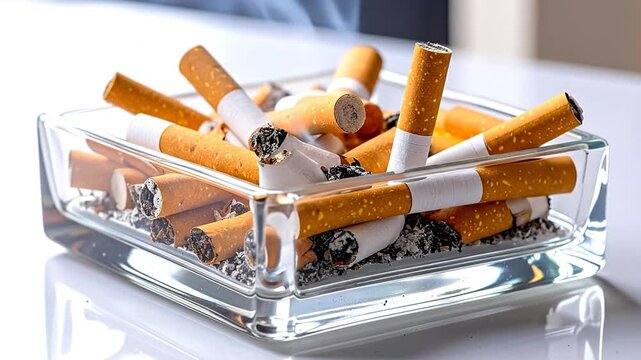 Close-up of a glass ashtray filled with numerous extinguished cigarette butts, some with ash still present