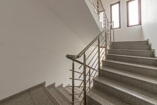 Modern stair case between floors. Stairs with metallic rail in modern building. Interior of a contemporary apartment or office building. Architecture and real estate background.