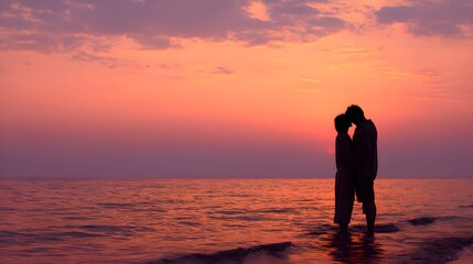 Silhouetted couple shares an intimate moment standing in shallow ocean water during a vibrant sunset