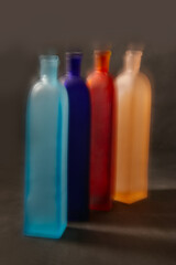  Four vintage bud vases of frosted glass of different colors with effects blurs in motion on dark background