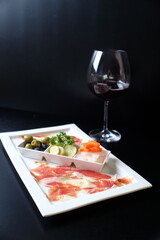 Gourmet meal with wine, an appetizing food composition and red wine glass. The picture has high key with contrast between food and the wine glass and its surrounding