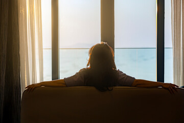 Simple lifestyle take it easy relaxation of Businesswoman looking outside hotel window Inspirational ocean beach sunset view, enjoying her summer vacation in luxury hotel. Twilight sky, Copy space