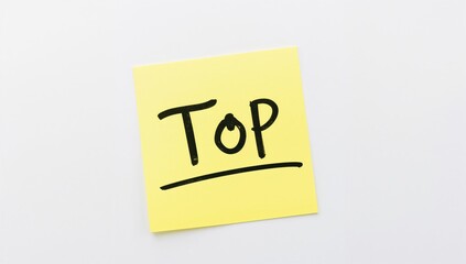 Yellow sticky note displaying the word 'Top' written in marker on a white surface.