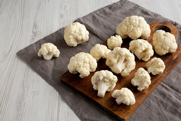 White Organic Raw Cauliflower Florets on a Wooden Board, side view.