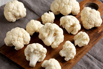 White Organic Raw Cauliflower Florets on a Wooden Board, side view.