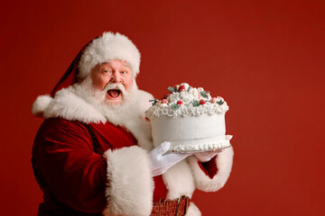 Santa Claus in a red suit with a huge fluffy beard holds a cake in his hands. Bakery delivery, Wedding planning services holiday matrimonial advertising or seasonal bakery marketing campaigns