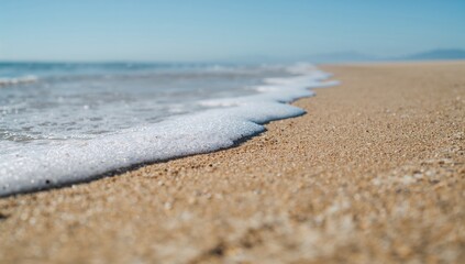 Sunlit sandy shore with gentle waves and empty space