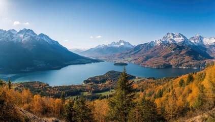Fototapeta premium Wide-angle scenery of a serene lake surrounded by autumn foliage in vibrant golden hues.
