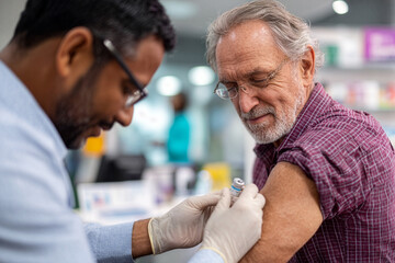 Senior man receiving flu shot from pharmacist at community pharmacy