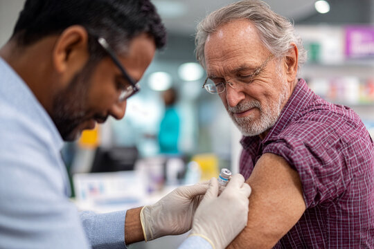 Senior man receiving flu shot from pharmacist at community pharmacy