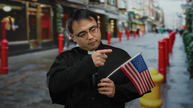 Priest holding american flag on urban street with red bollards and blurred city background, depicting multicultural setting