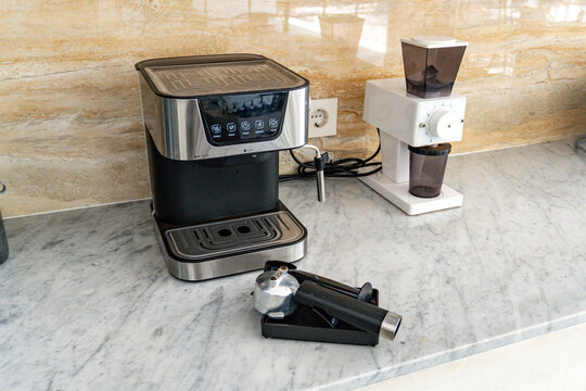 Modern espresso machine and electric burr coffee grinder on a marble kitchen counter, ready for home brewing and making a fresh cup of coffee