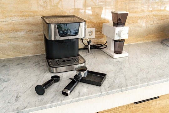 Modern espresso machine and electric burr coffee grinder on a marble kitchen counter, ready for home brewing and making a fresh cup of coffee