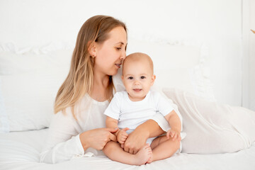 mother and baby hugging and kissing on the bed at home, maternal love and care, mother and child