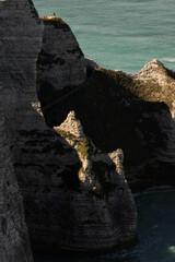 Famous white cliffs of Étretat, Normandy, France, rising above turquoise sea waters. Iconic coastal landscape known for its natural beauty and dramatic rock formations.