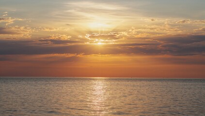 Fototapeta premium A breathtaking evening sky glows over a tranquil seaside, with vibrant colors mirrored on the calm water.