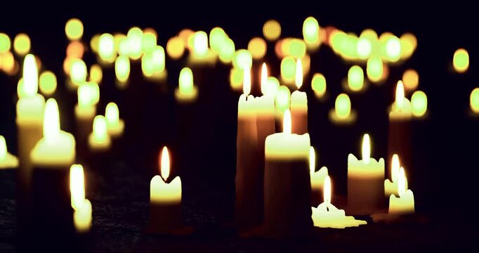 Soft candlelight fills a serene environment, casting gentle shadows as people gather for reflection. The warm glow creates a peaceful atmosphere perfect for relaxation or contemplation.