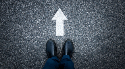 Man standing on asphalt road with the arrow sign