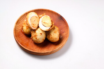 A top-down view of several hard-boiled eggs coated in a light brown sauce on a wooden plate, with two eggs cut in half showing the yolk.