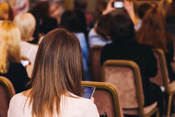 Female audience at the symposyum meeting, participants attendees in conference room hall listens to...