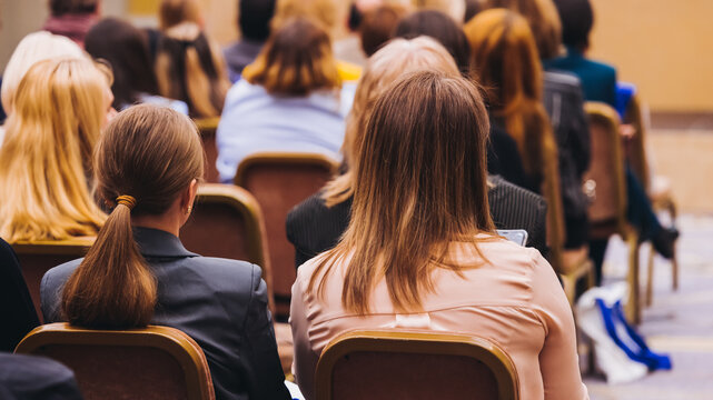 Female audience at the symposyum meeting, participants attendees in conference room hall listens to lecturer, group of women on a medical congress together listen to speaker on a stage at master-class