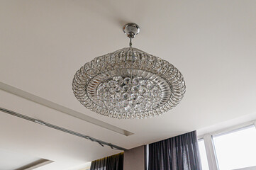 Elegant crystal chandelier hanging from a white ceiling. Its round design features multiple tiers...