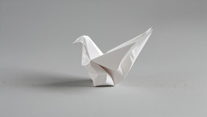 Origami dove crafted from white paper on a plain grey backdrop