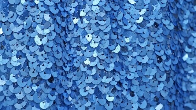 Close-up shows overlapping, iridescent blue sequins. Textured, glittering surface with slight depth and curves