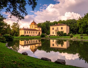 Elegant waterside estate reflects in a calm lake, framed by trees and a dramatic sky