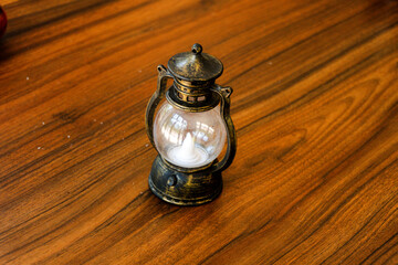 Vintage mini lantern with a flickering LED candle on a rich wooden table, evoking a cozy, rustic, and warm atmosphere