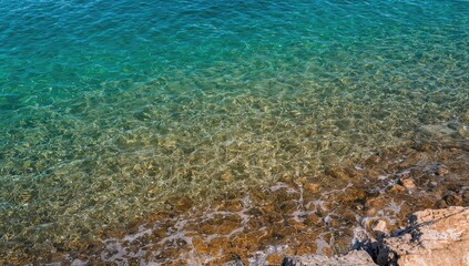 Fototapeta premium Crystal Clear Ocean Water with Coastal Stones and Tranquil Vibes