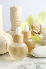 Beautiful spa composition with essential oils and herbal bags on white marble table, closeup
