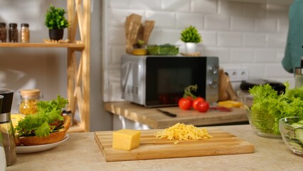 A modern kitchen with fresh vegetables, cheese, and a microwave, showcasing a cozy cooking environment.