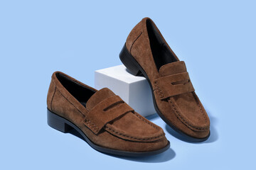 Pair of stylish brown shoes on light blue background