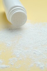 Bottle of talcum powder on yellow background, closeup