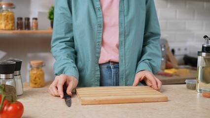 A woman standing in a kitchen with a cutting board and knife, ready to prepare food ingredients. Preparing a healthy breakfast or snack in the kitchen at home.