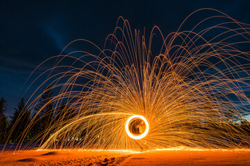 Creating light art with steel wool in a snowy landscape at night