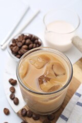 Tasty iced coffee with milk and beans on white table, closeup
