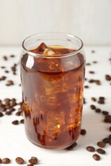 Tasty iced coffee and beans on white wooden table