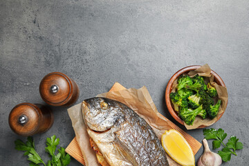 Tasty grilled fish, broccoli and spice on grey table, flat lay. Space for text