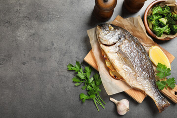 Tasty grilled fish, broccoli and spice on grey table, flat lay. Space for text