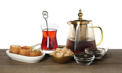Traditional Turkish tea, desserts, dry leaves and sugar on wooden table against white background