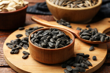 Unpeeled sunflower seeds on wooden table, closeup