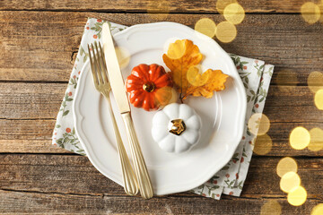 Autumn table setting, bokeh lights. Plate, cutlery and decor on wooden table, top view