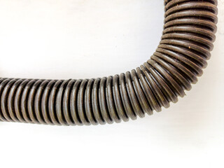 Close-up of flexible corrugated plastic tubing (conduit) curved on a white background. Represents industrial installation, electricity, plumbing, technology, and engineering.