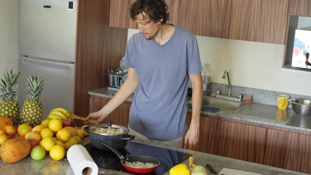 A young man is cooking food in the kitchen, focusing on preparing a delicious homemade meal. A relatable and warm moment of homemaking, creativity, and culinary enjoyment in a cozy setting.
